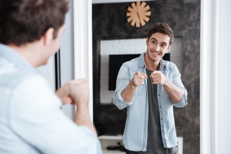 graphicstock-smiling-young-man-pointing-fingers-at-his-mirror-reflection-while-standing-at-home_B_G0UO3I2g